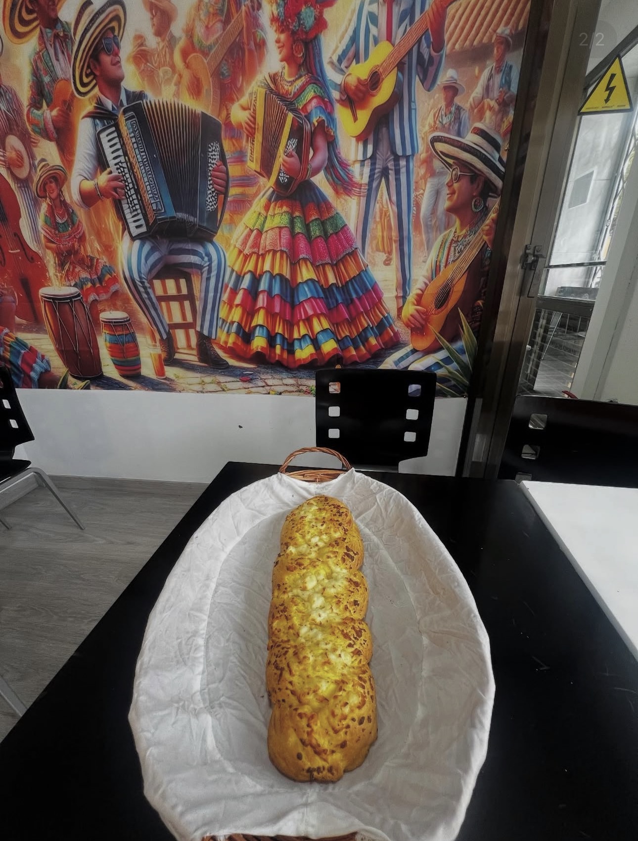 Pan de queso recién horneado frente al mural colombiano de El Parxhe 83